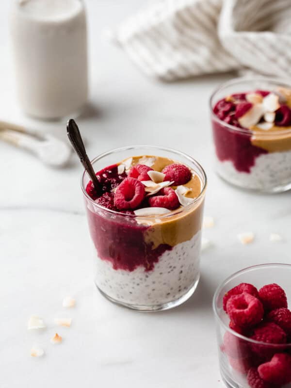 A cup of peanut butter overnight oats with jam and raspberries