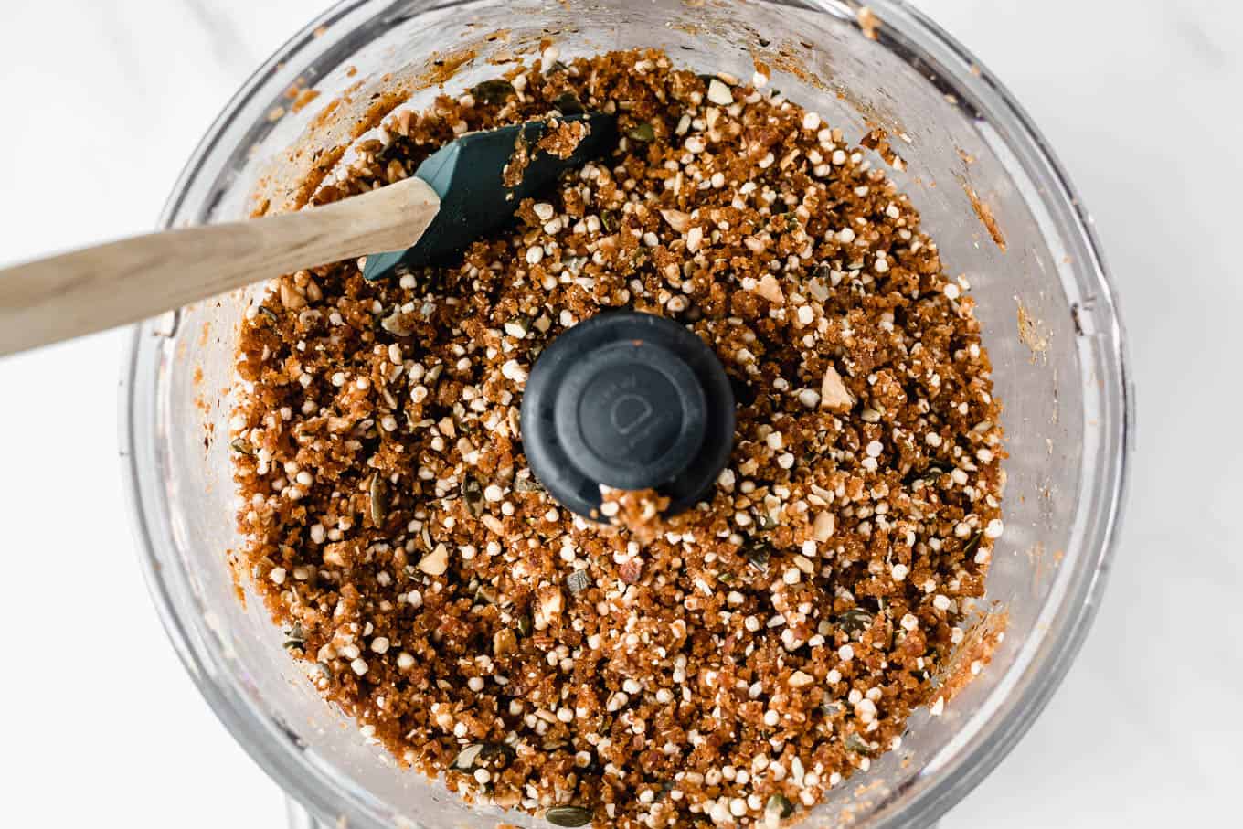 A food processor with quinoa date and nut bars dough in it