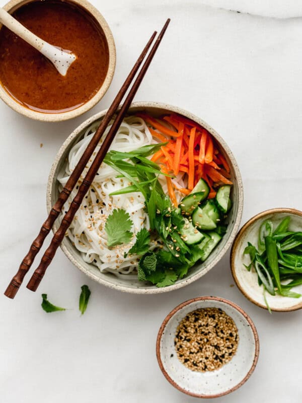 A spring roll noodle bowl with almond butter sauce on the side