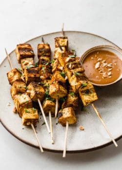 tofu satay skewers on a plate with peanut sauce
