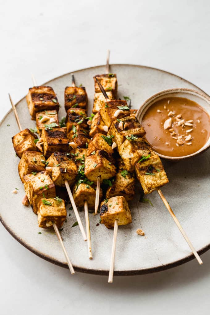 tofu satay skewers on a plate with peanut sauce