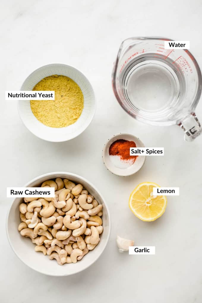 raw cashews, nutritional yeast, spices and water on a marble board