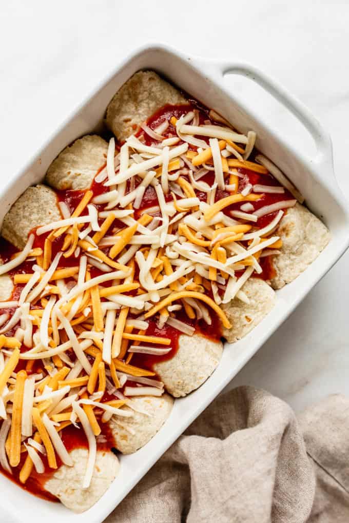 veggie enchiladas uncooked topped with shredded cheese