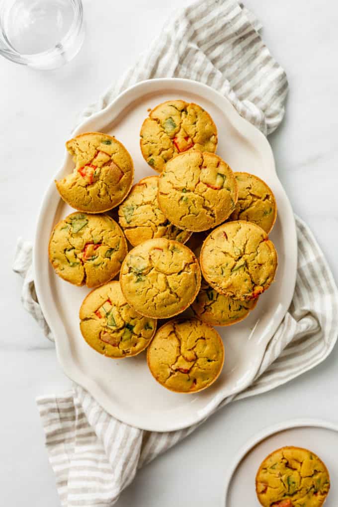 a stack of mini chickpea flour quiches on a white platter over a striped napkin
