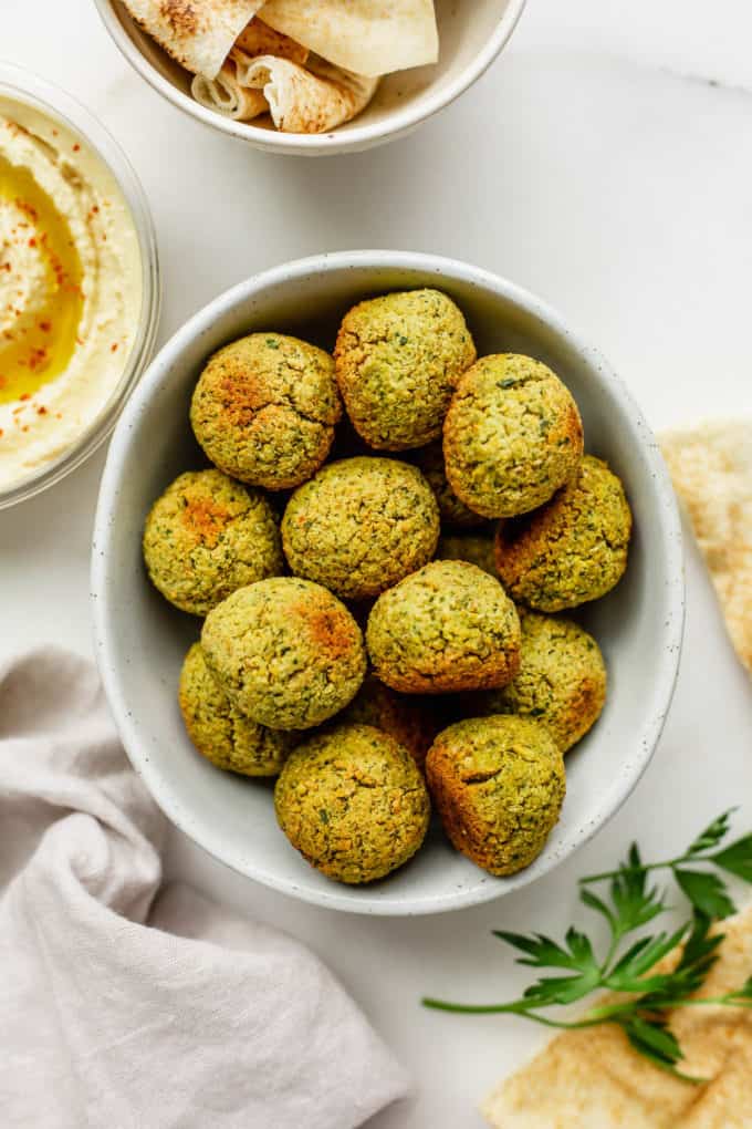 A bowl of baked falafel with pita and hummus on the side