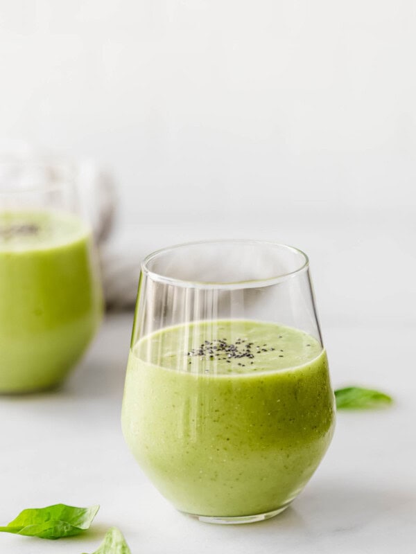 Two glasses with green smoothie in them topped with chia seeds