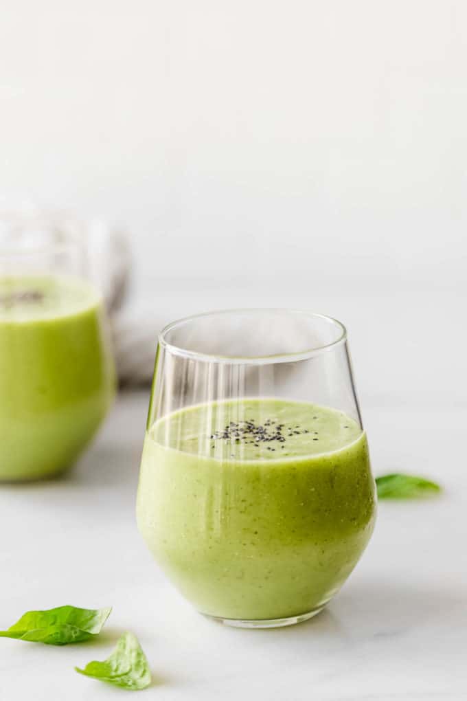 Two glasses with green smoothie in them topped with chia seeds