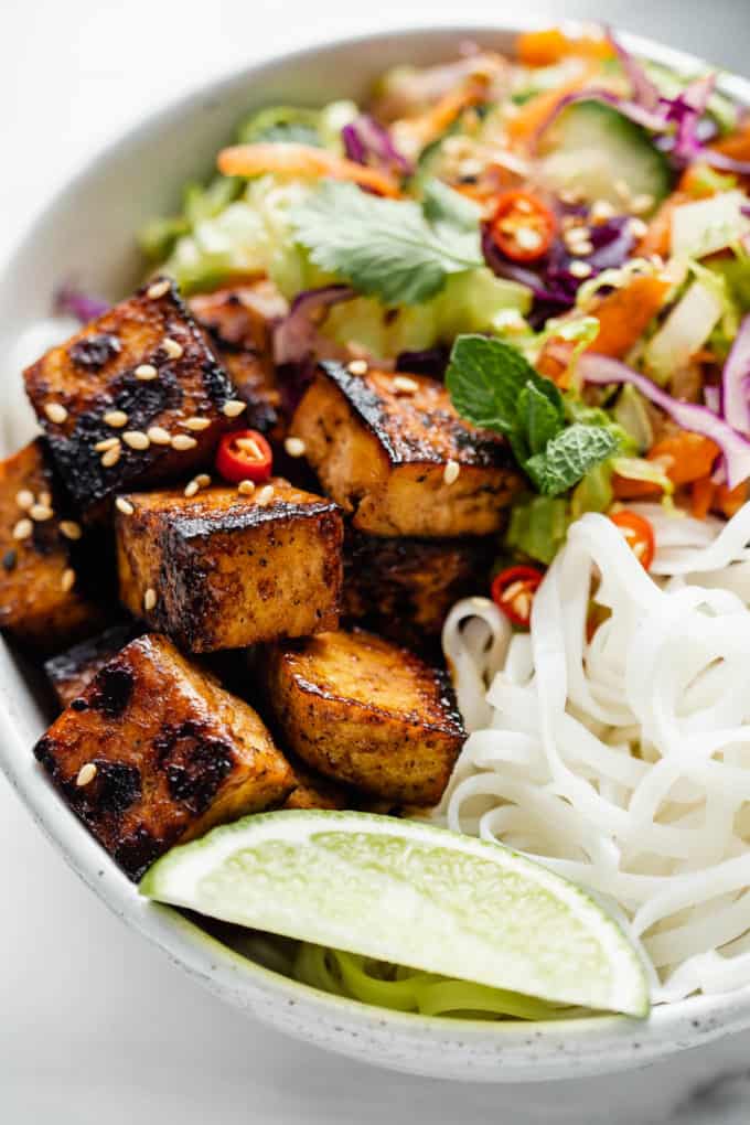 lemongrass tofu, a lime, rice noodles and salad in a bowl