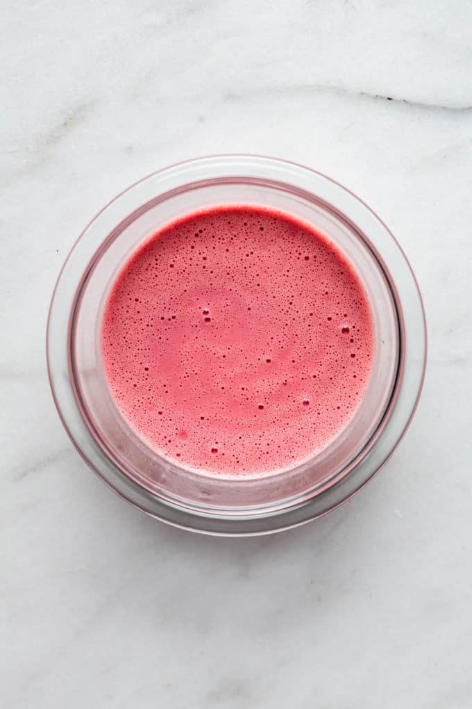 blended raspberries and almond milk in a clear mixing bowl