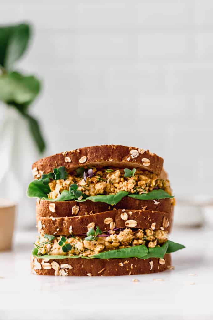 two chickpea salad sandwiches stacked on a marble counter