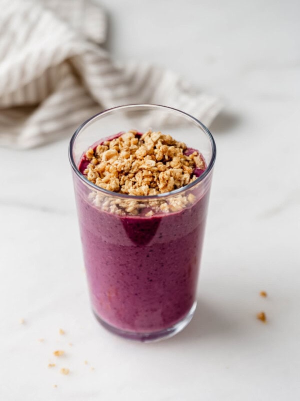 An acai smoothie in a glass topped with granola