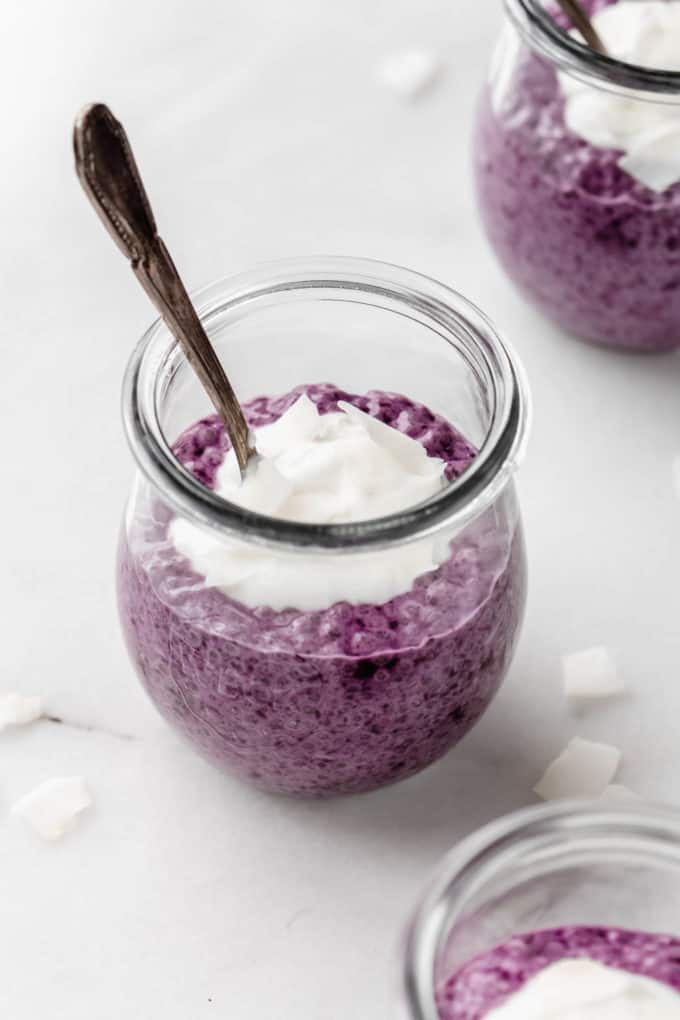 a cup of blueberry chia pudding topped with coconut flakes