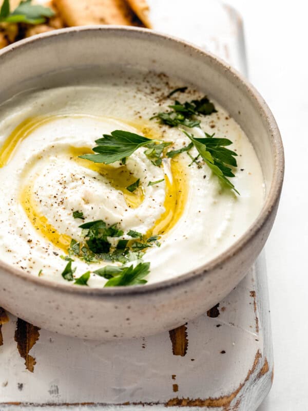 A bowl of whipped feta dip with olive oil and parsley on top