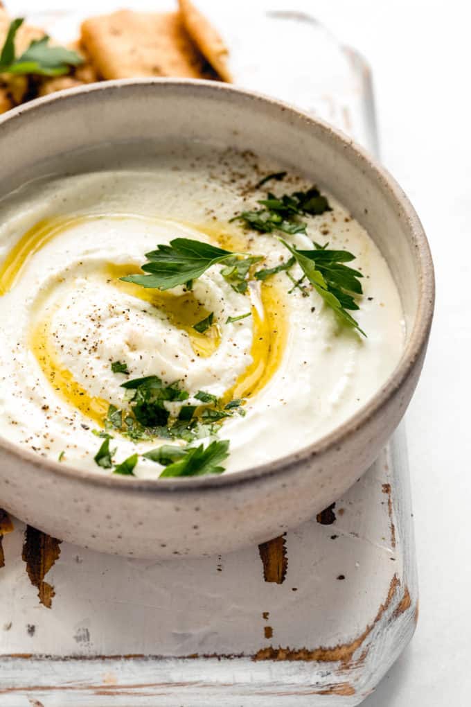 A bowl of whipped feta dip with olive oil and parsley on top