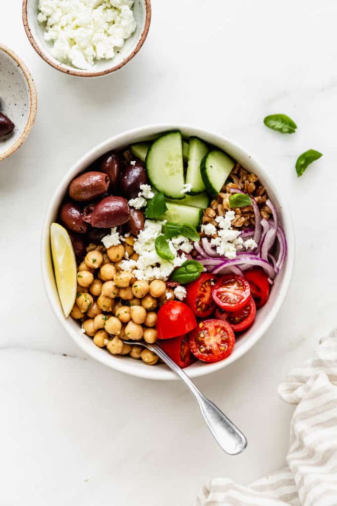 A bowl filled with farro, chickpeas and vegetables with a napkin on the side