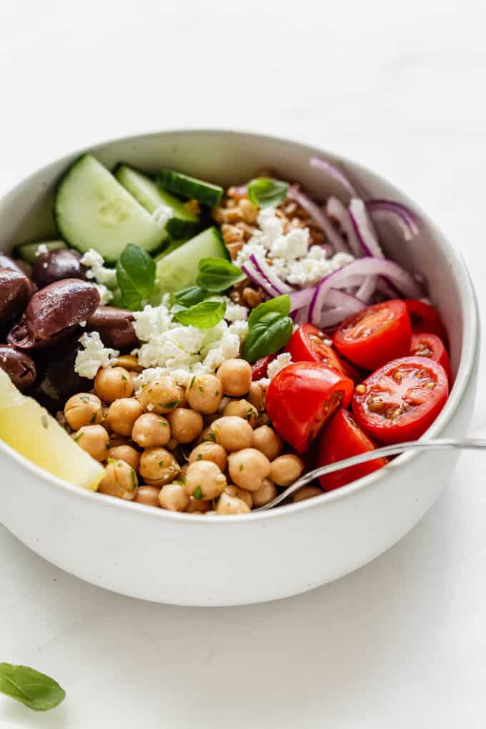 A greek power bowl with chickpeas and vegetables in a white bowl