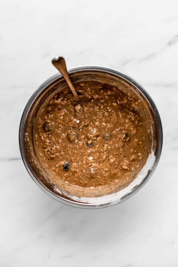 A mixing bowl with blueberry muffin batter in it