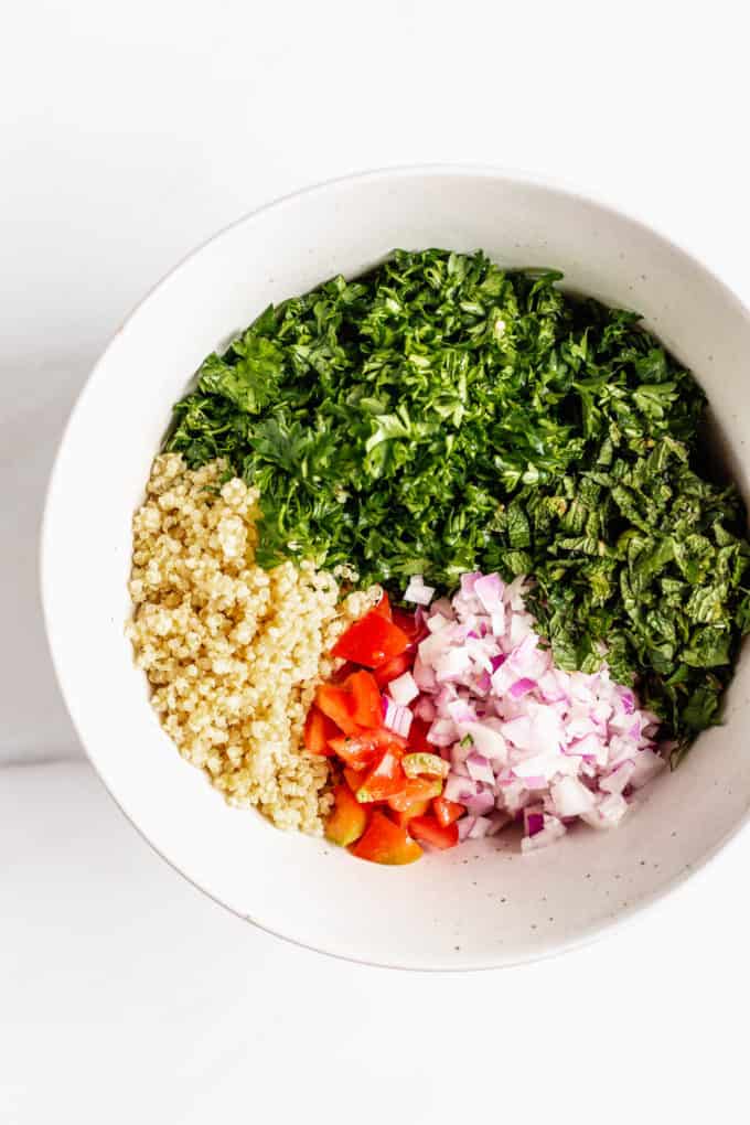 Parsley, mint, red onion, red pepper and quinoa in a mixing bowl