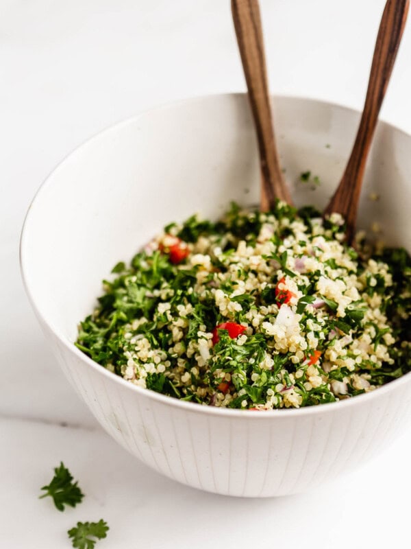 A bowl of quinoa tabbouleh salad with wood serving spoons