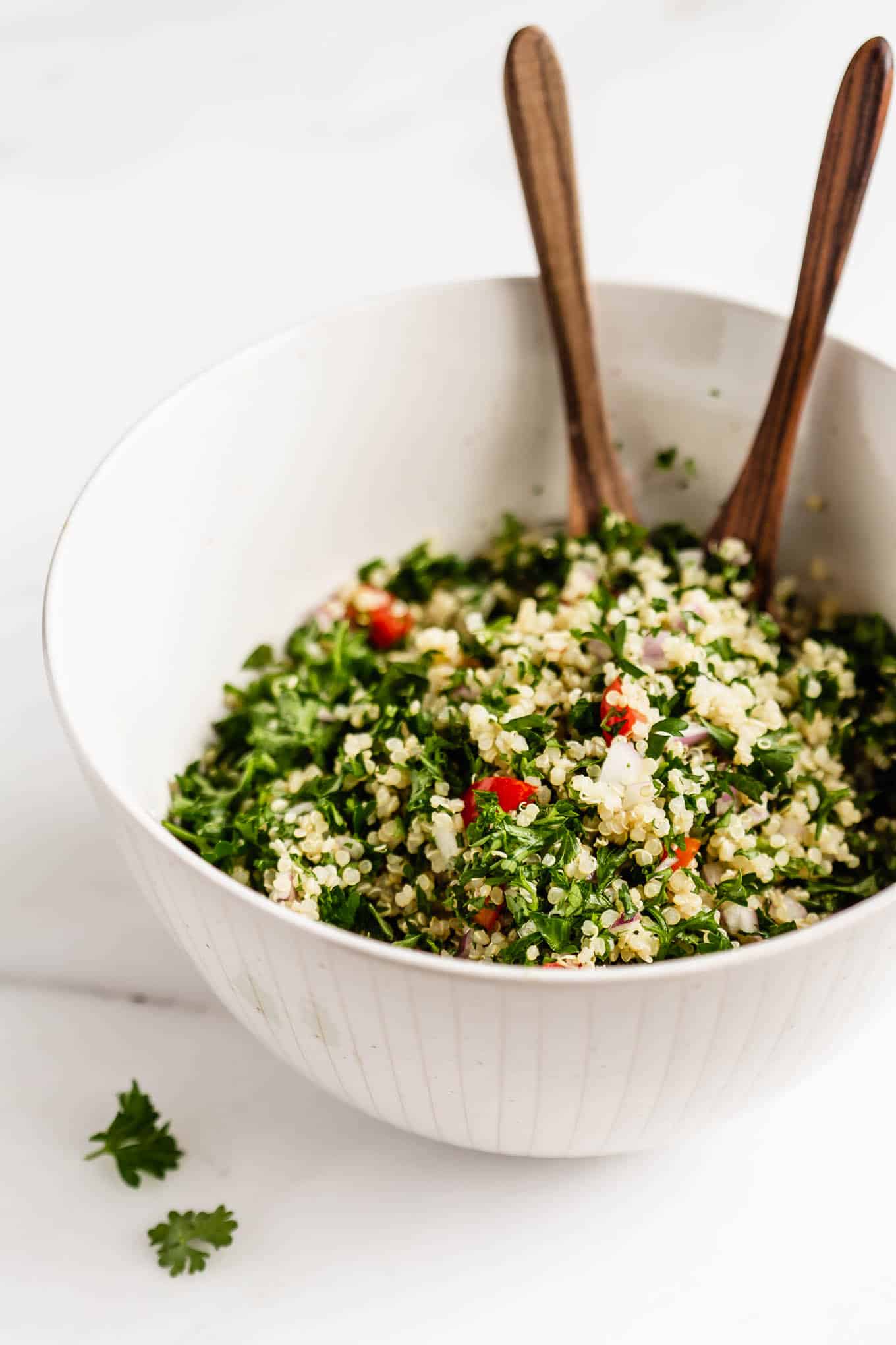 A bowl of quinoa tabbouleh salad with wood serving spoons