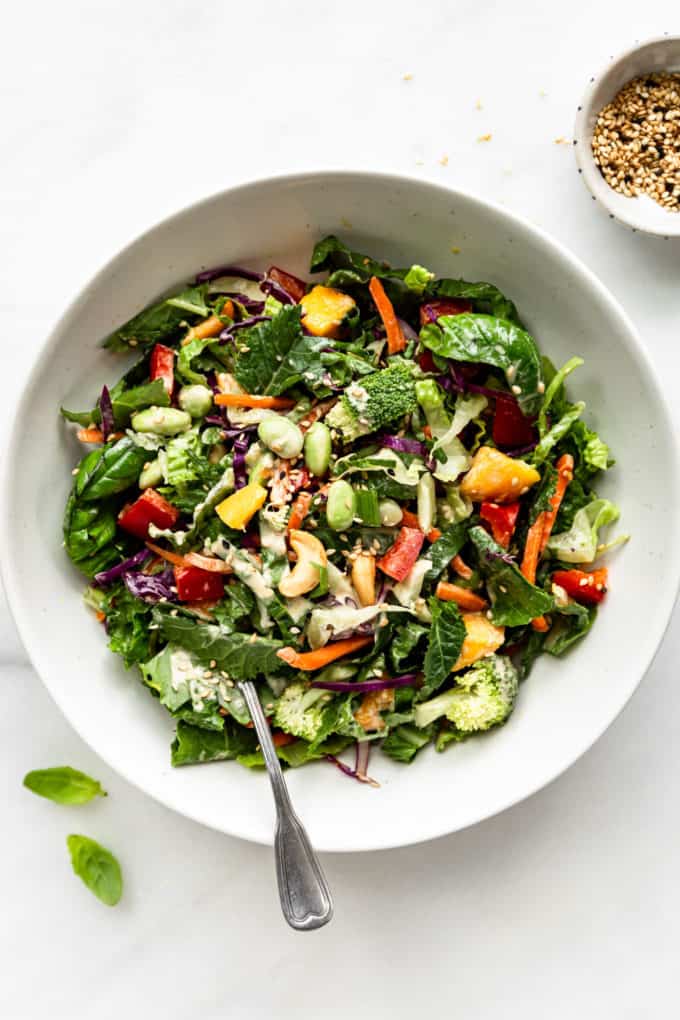 A Thai Crunch Salad with Sesame dressing in a white bowl with a fork in it
