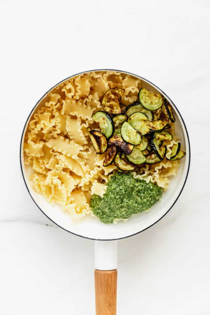 Noodles, roasted zucchini and pesto in a white pot