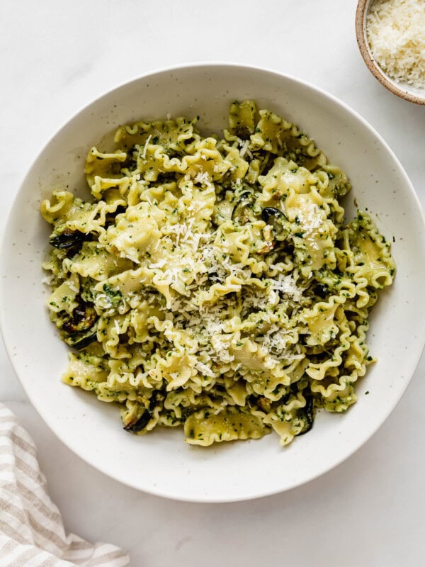 Veggie pesto pasta in a white bowl topped with parmesan cheese