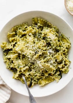 Pesto pasta in a bowl with a fork in it