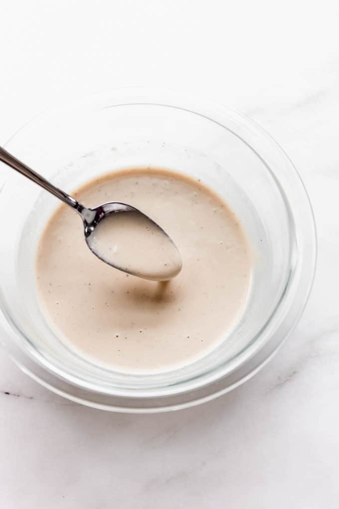 a spoon scooping lemon tahini dressing out of a bowl