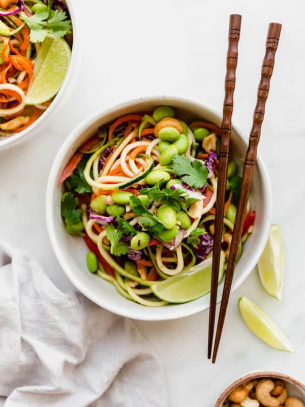 Raw pad Thai in a white bowl with wooden chopsticks on the side
