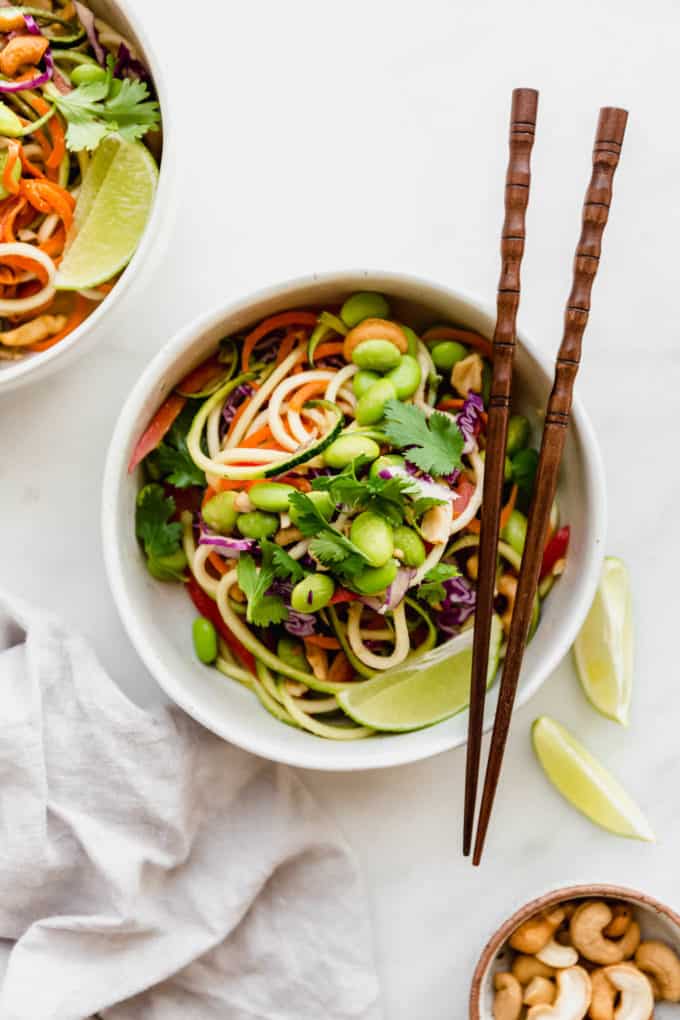 Raw pad Thai in a white bowl with wooden chopsticks on the side