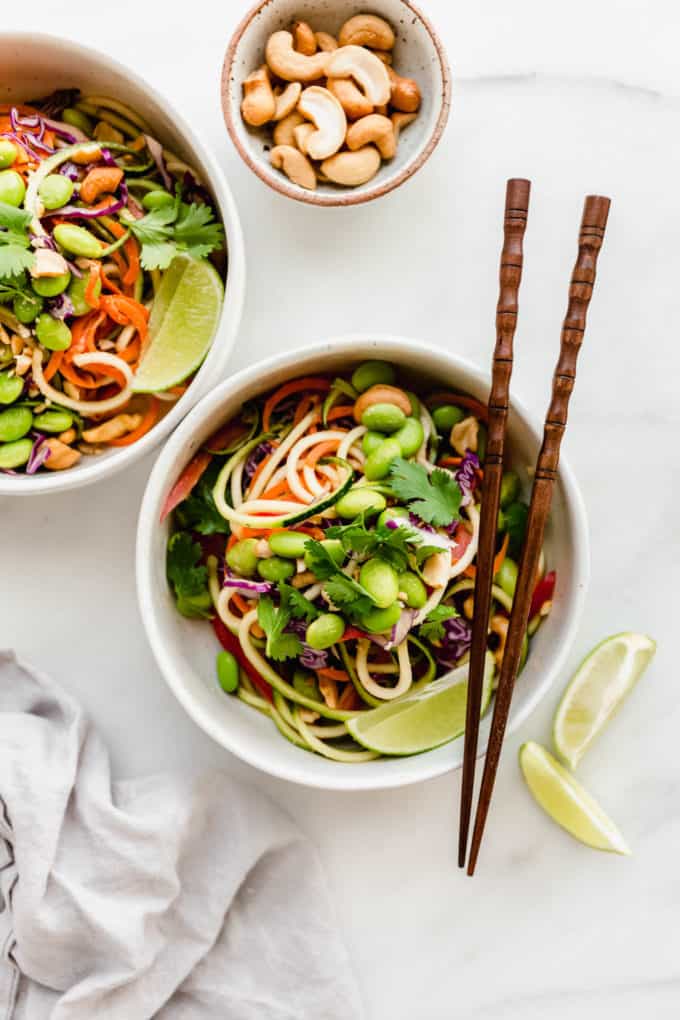 Two bowls of raw pad Thai made of spiralized zucchini topped with edamame