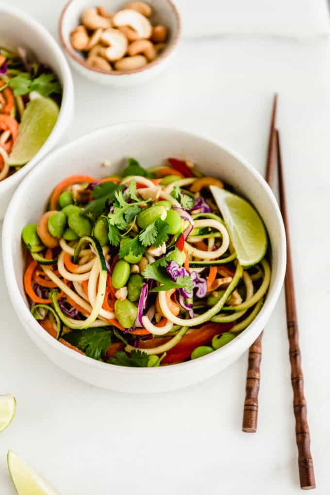 A bowl of spiralized zucchini and carrots topped with edamame and cilantro