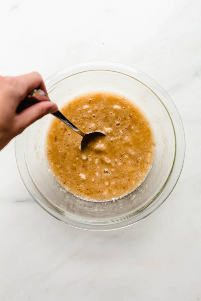 Mashed bananas and eggs in a clear mixing bowl