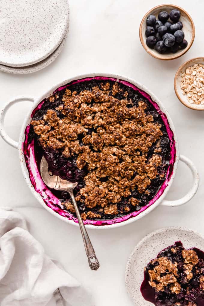 A blueberry crisp dishes and a napkin on the side