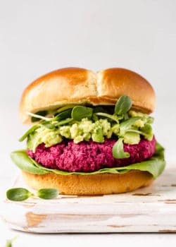 A vegan beet burger in a bun with avocado, sprouts and lettuce