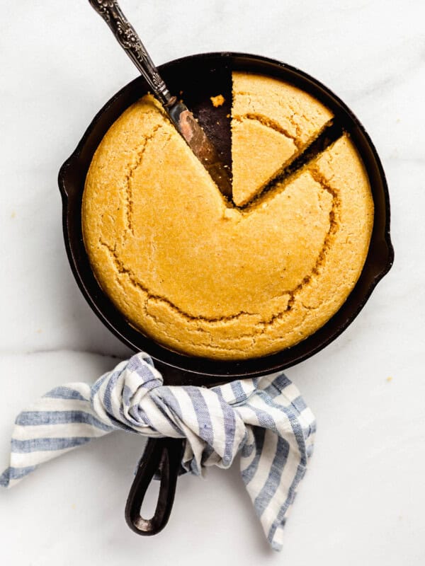 Cornbread in a cast iron skillet with a blue striped napkin tied around the handle