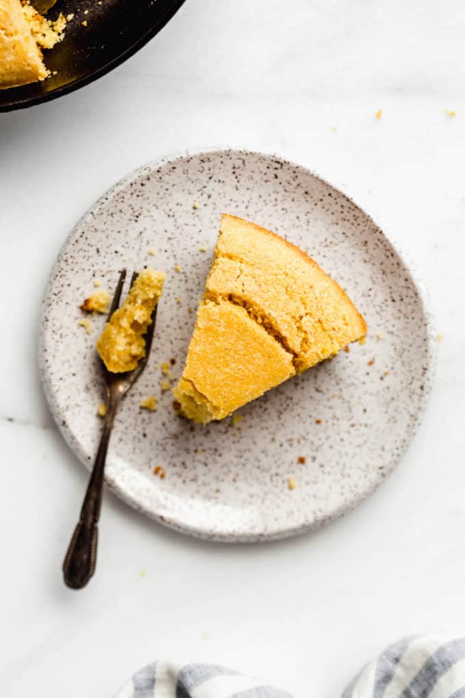 A slice of cornbread on a white ceramic plate
