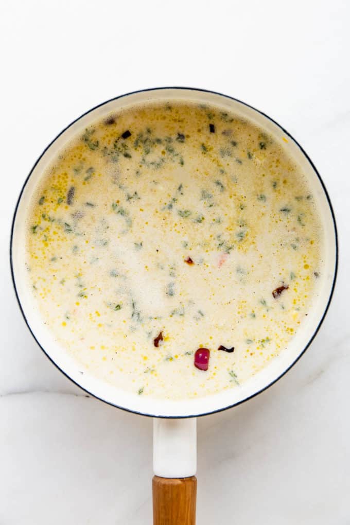A white pot with veggie broth and cashew cream in it