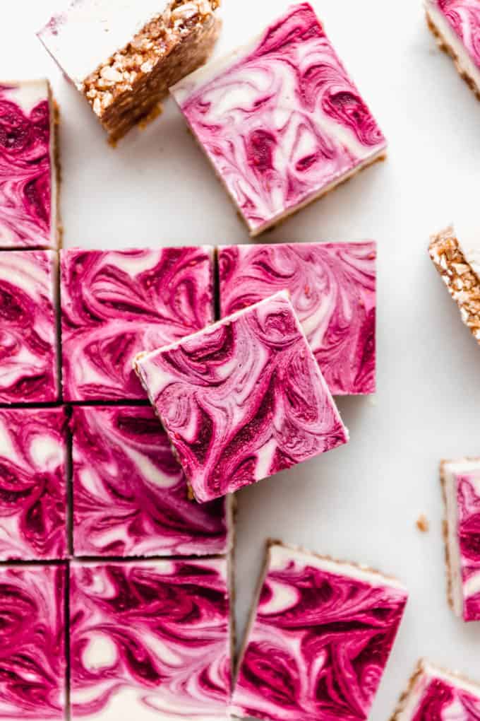 Vegan raspberry cheesecake bars cut into squares on a marble board