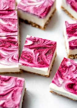 Vegan raspberry cheesecake bars with raspberry swirl on top on them