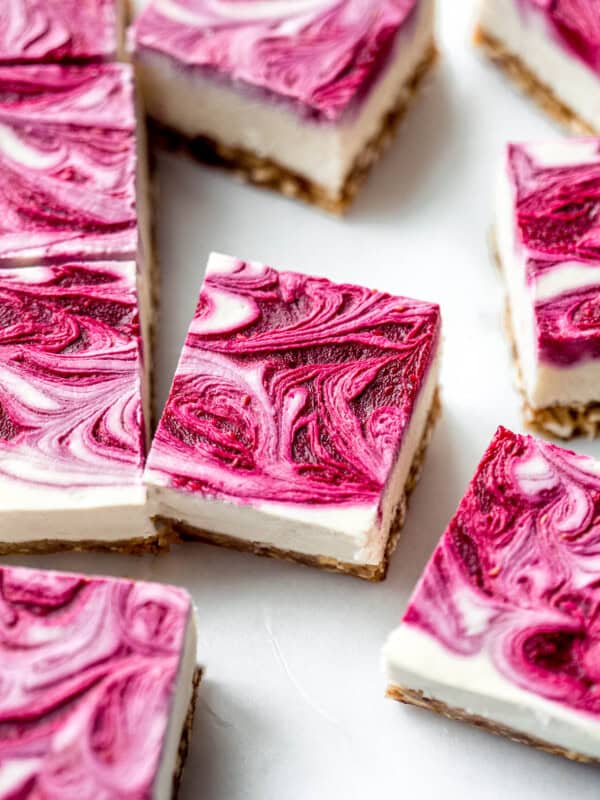 Vegan raspberry cheesecake bars with raspberry swirl on top on them