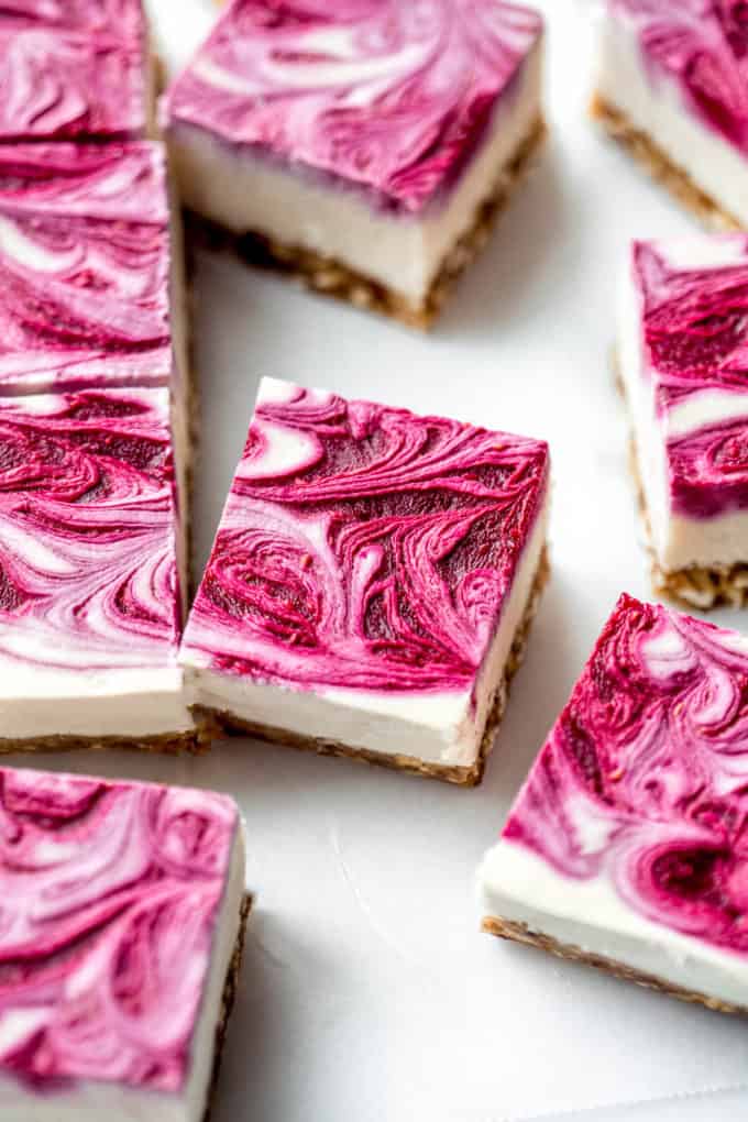 Vegan raspberry cheesecake bars with raspberry swirl on top on them