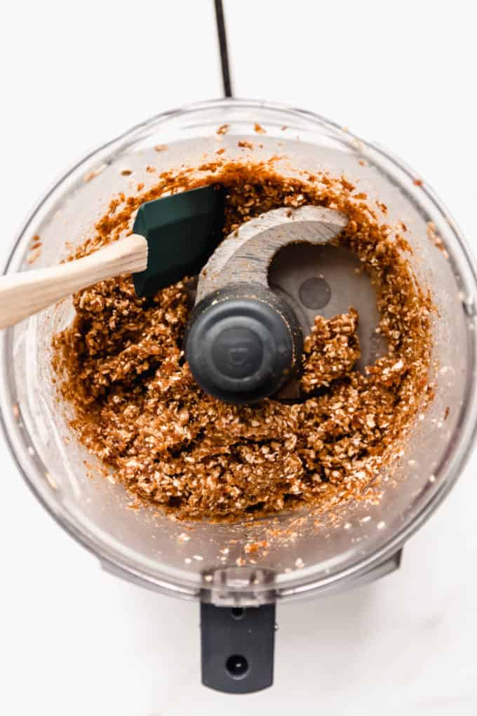 A food processor with blended date, walnuts and oats in it