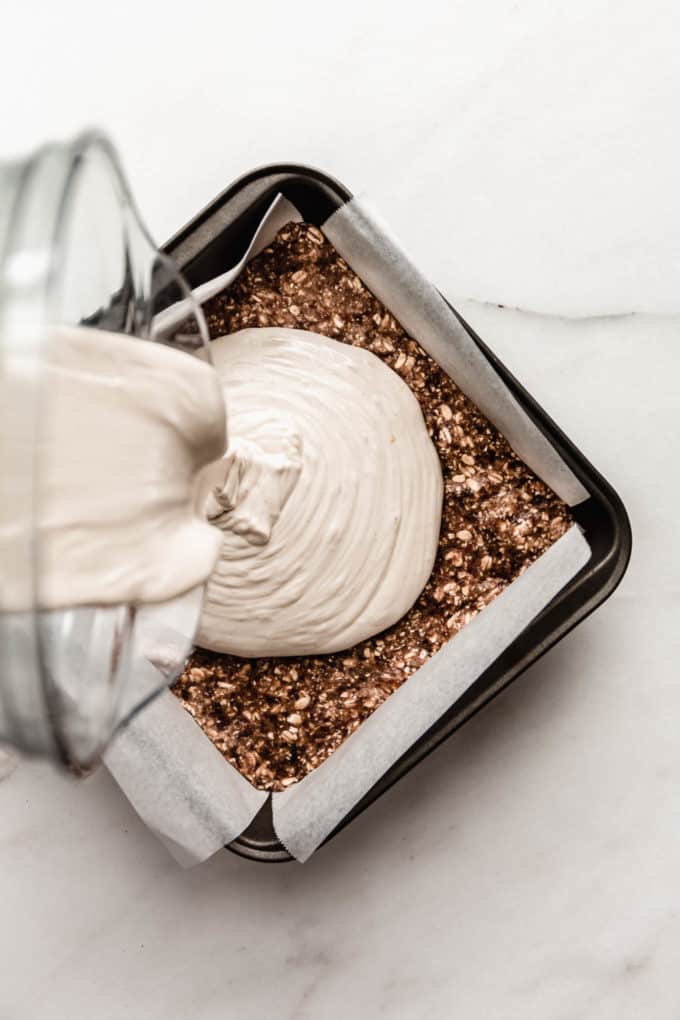 vegan cheesecake filling being poured into an 8x8 inch pan