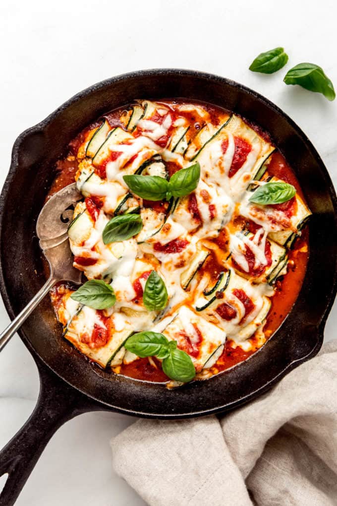 Zucchini involtini in a cast iron skillet topped with fresh herbs