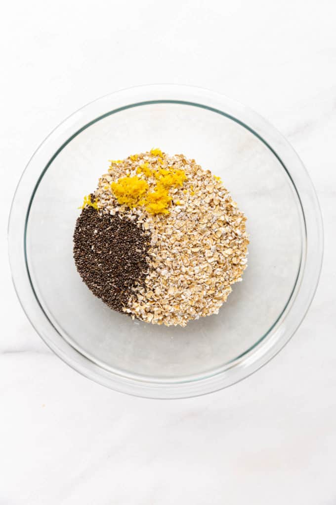 A clear mixing bowl with oats, chia seeds and lemon zest