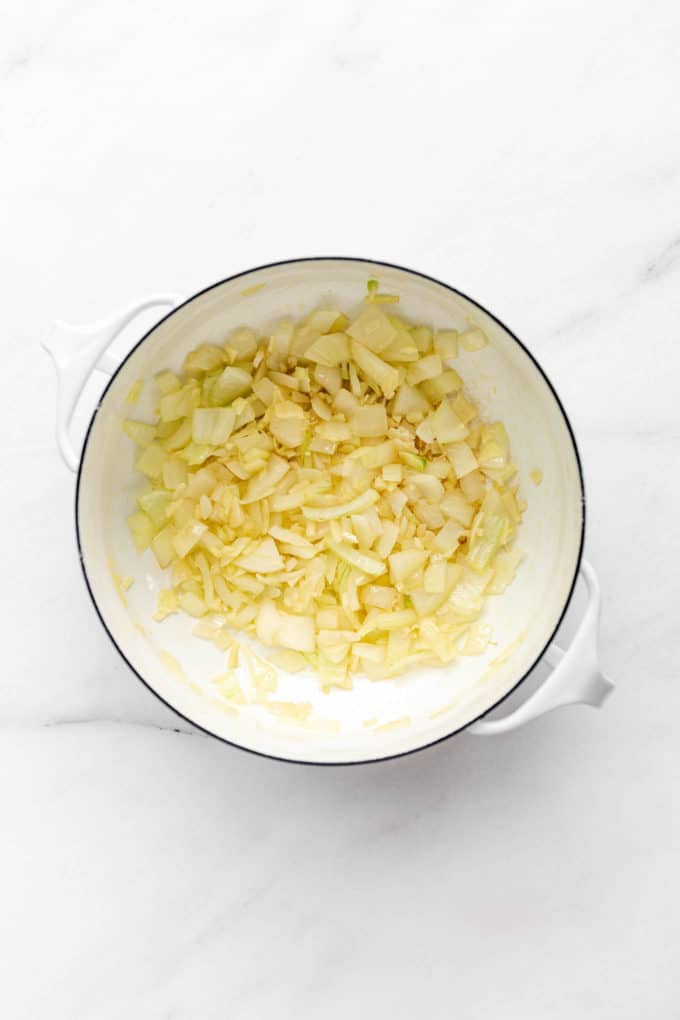 A white pot with sautéed onions in it