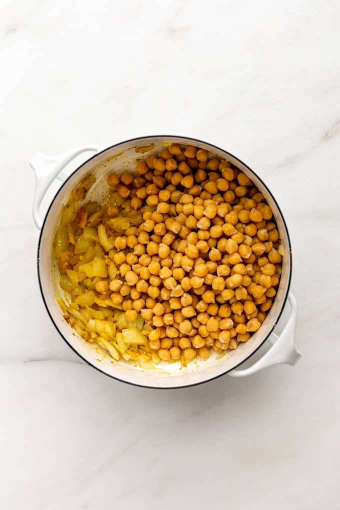A white pot with chickpeas and onions in it
