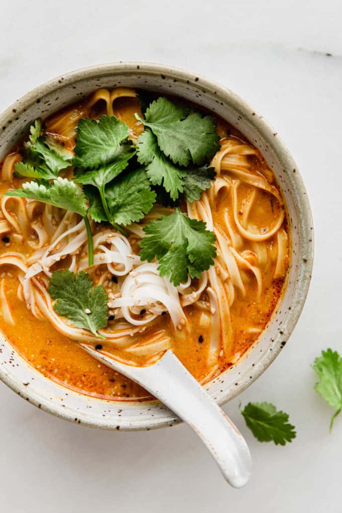 A bowl of Thai Coconut Soup with noodles and a soup spoon in it